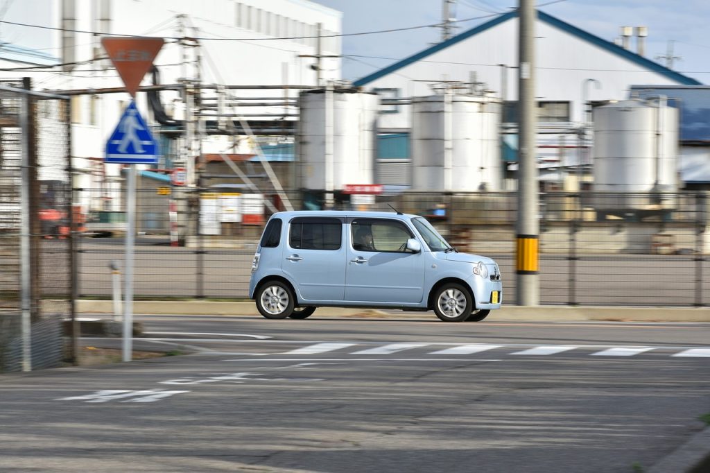 水色の軽自動車が走ってる画像