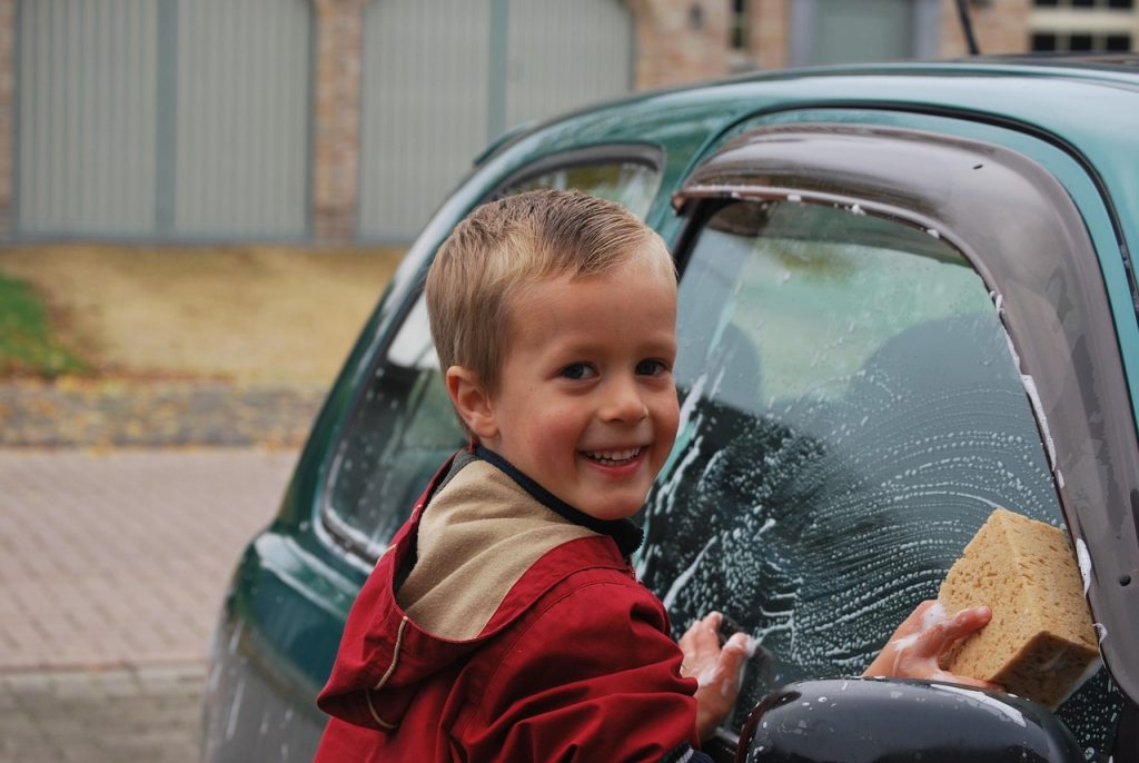 子供が楽しそうに車を洗車している画像